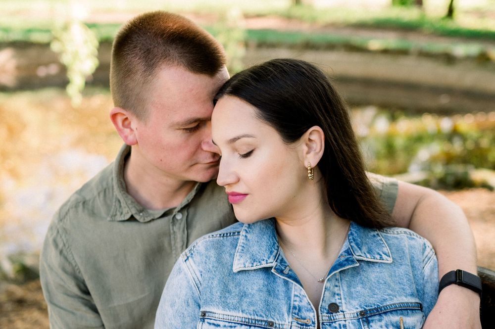 Intimate couple portraits captured in a sunlit outdoor setting with natural greenery.