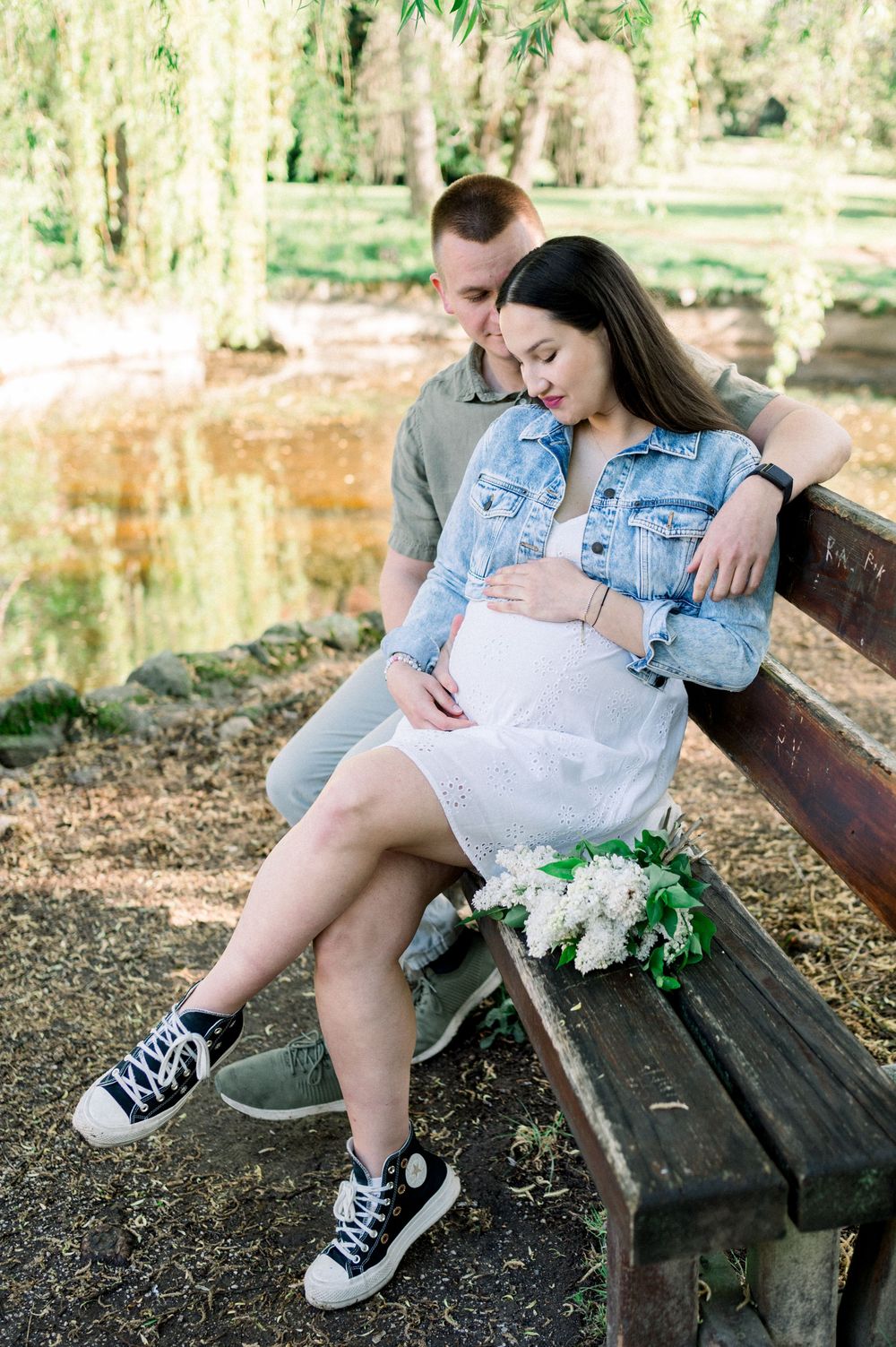 Couple sits together on a rustic wooden bench in a peaceful garden setting.