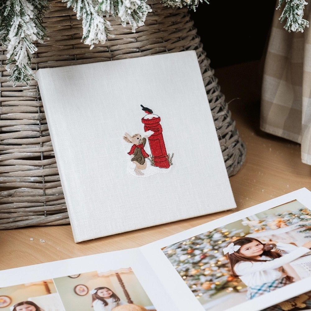 A series of holiday greeting cards displayed on a wooden surface with evergreen branches and festive decorations.
