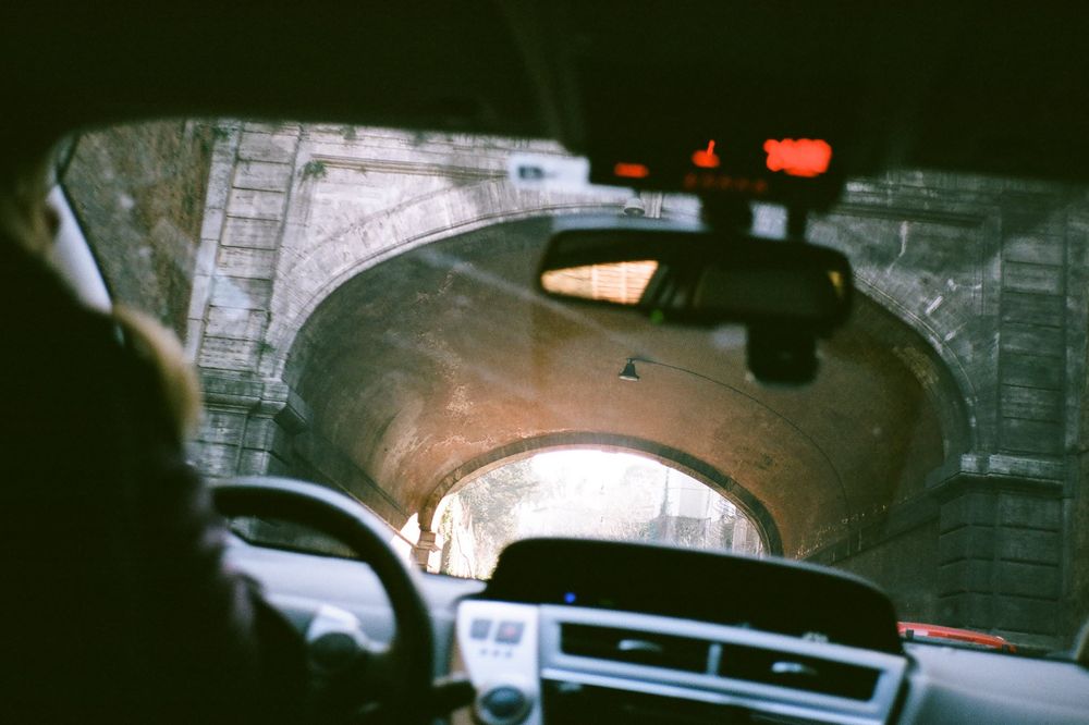 A dark security camera footage shows a car driving through what appears to be a parking garage or tunnel structure.