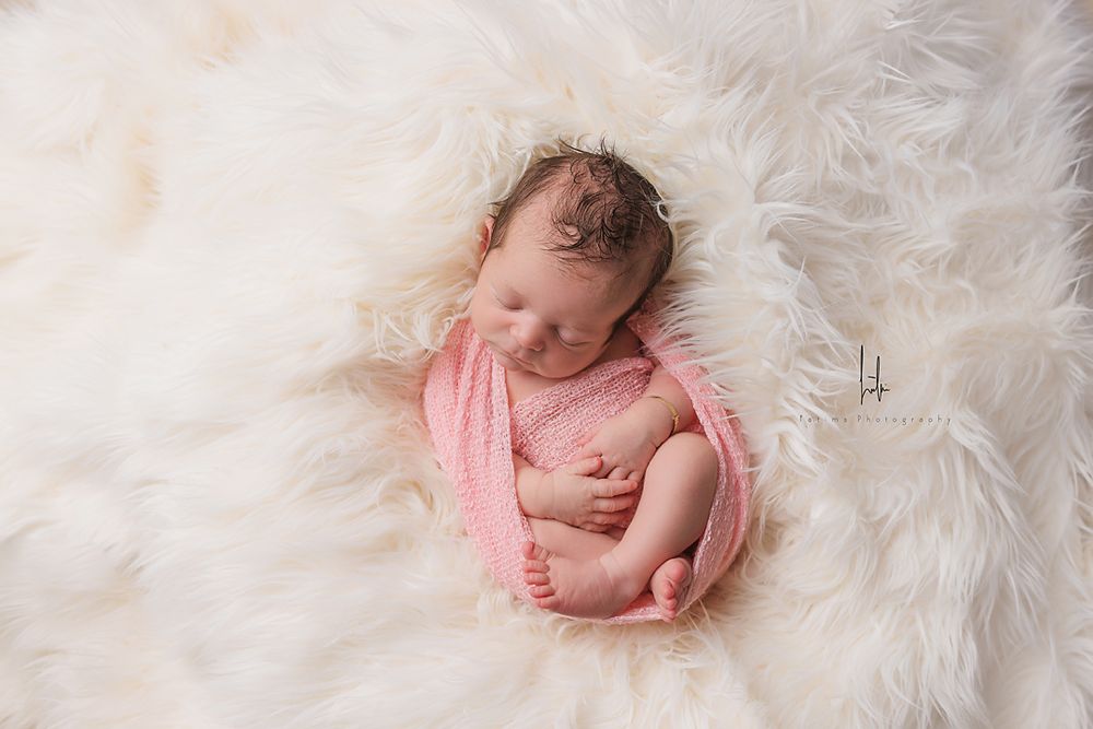 Five connected photos show a sleeping newborn baby posed on soft white fur in various peaceful positions.