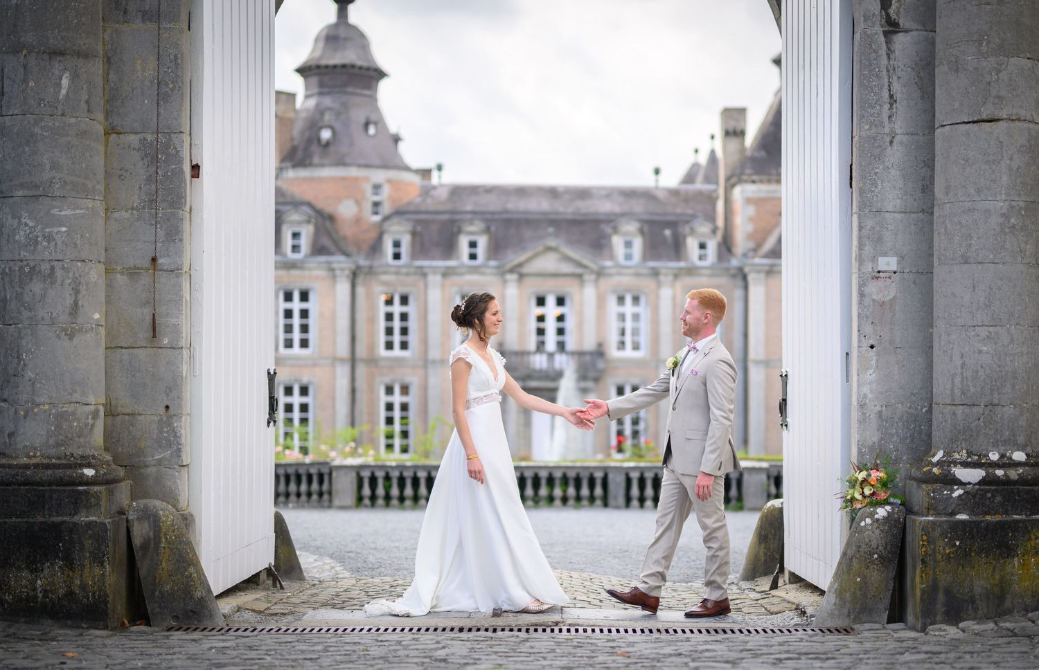 A romantic wedding couple poses in a series of elegant shots under stone archways at a historic European castle.