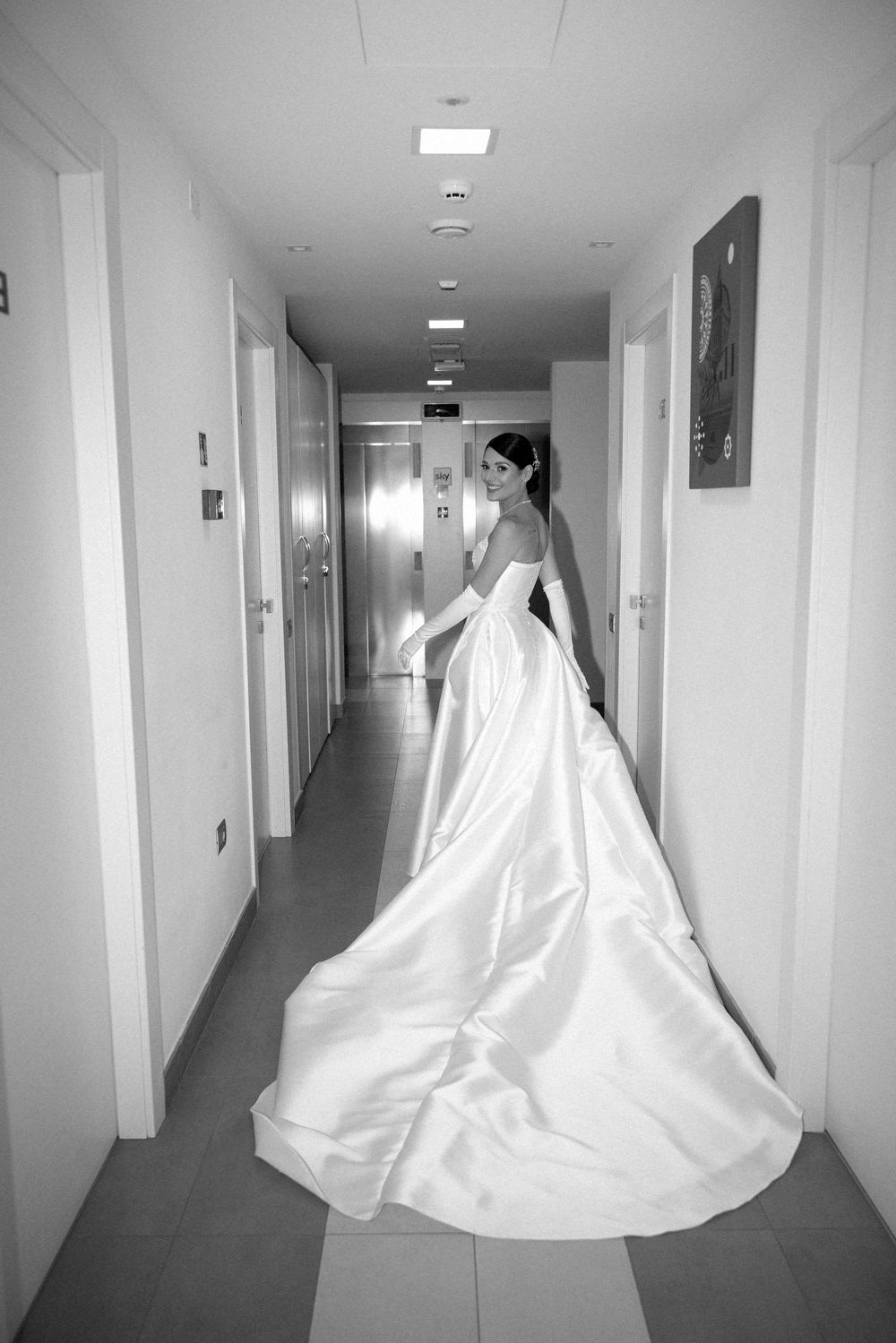 Black and white photos show a bride in a flowing white ballgown walking down a minimalist hallway.