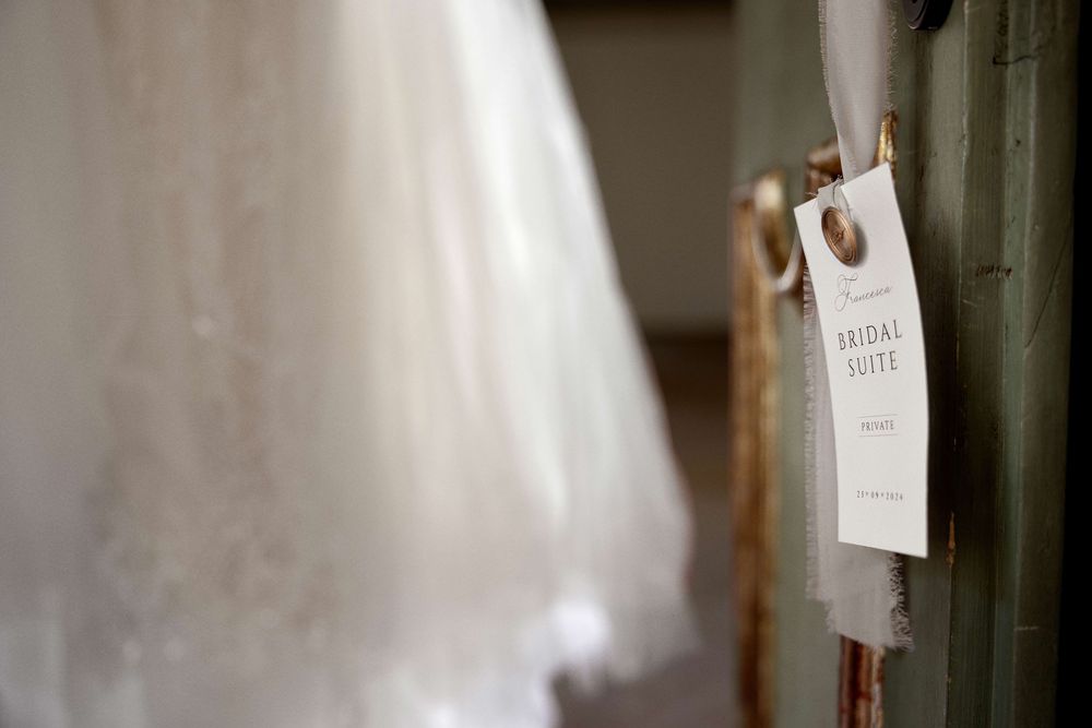 Rustic wooden door frame with vintage style paper tags hanging on strings against a white wall.