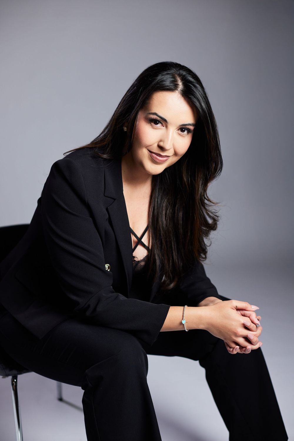 Elegant black blazer photoshoot with dramatic poses against grey studio backdrop.