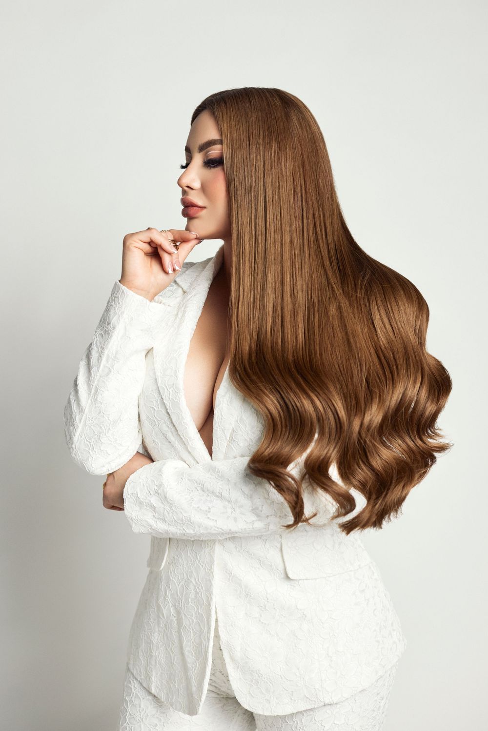Fashion portraits in white ensemble featuring styled wavy brown hair against light background.