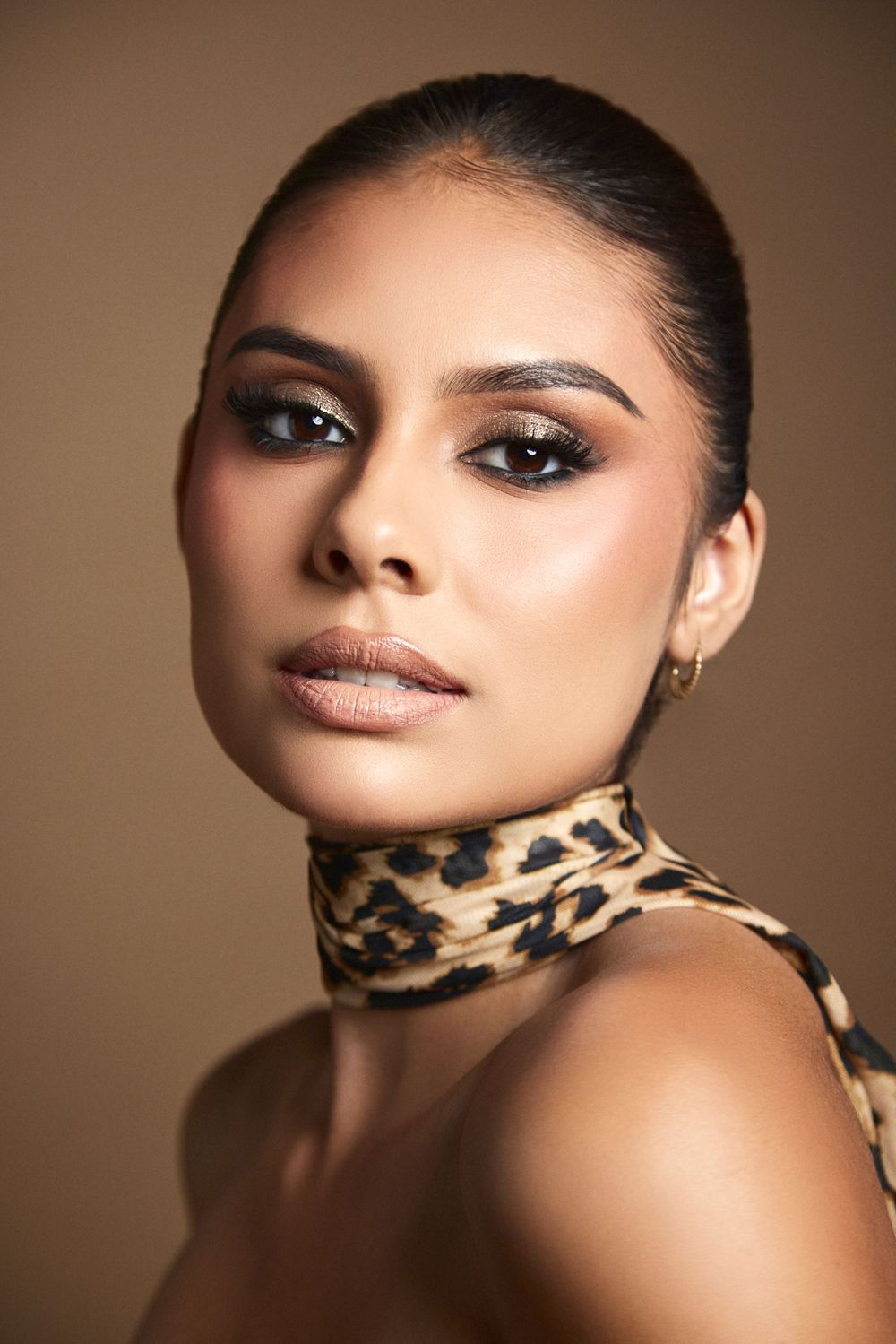 Close-up beauty portrait with leopard print accessory and glowing makeup.