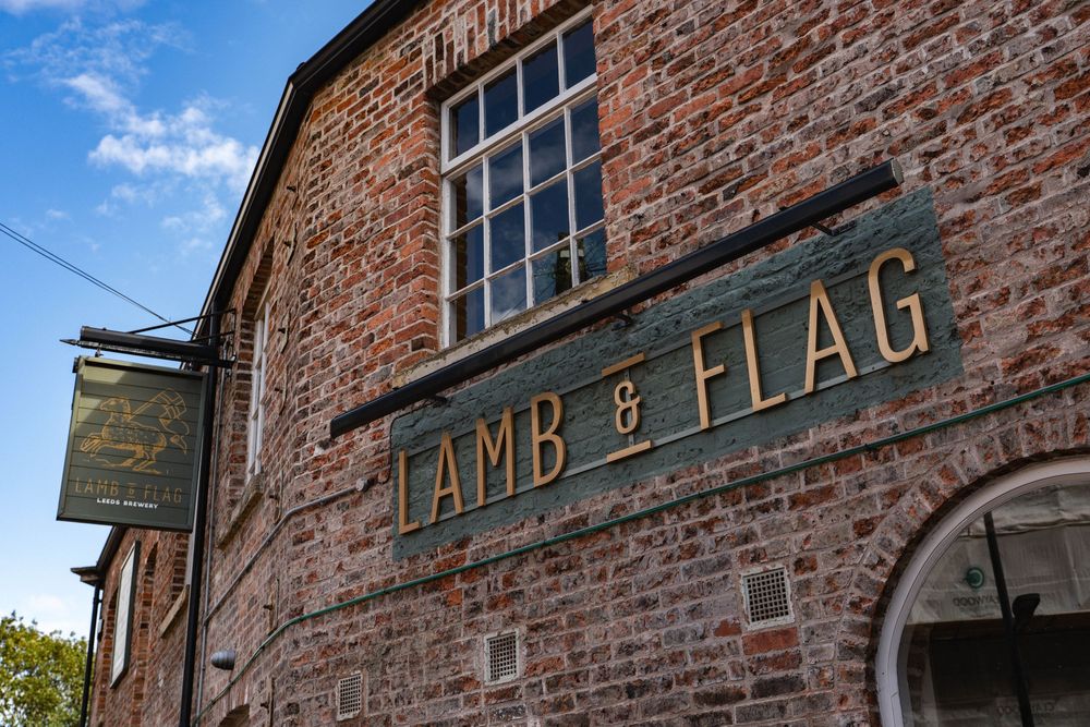 Exterior photography for pub branding,Historic red brick building facade with vintage signage and architectural details against a blue sky.