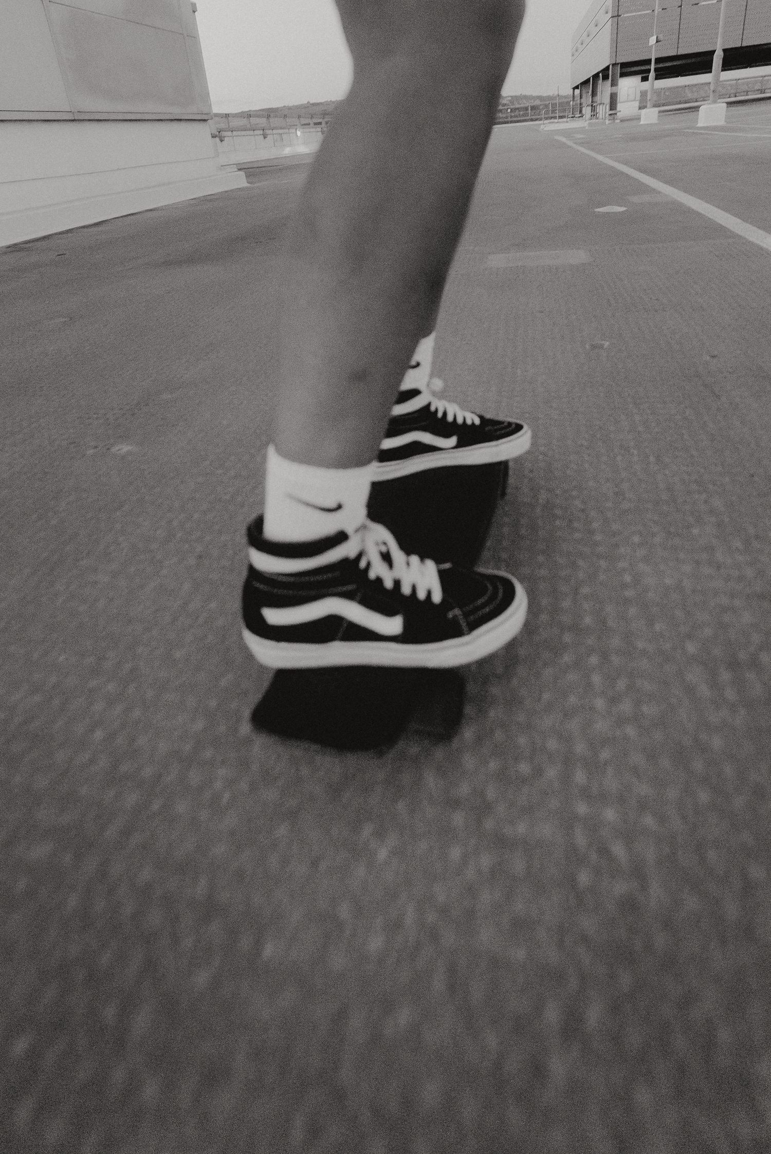 Close-up black and white shot of Vans sneakers on a skateboard deck.