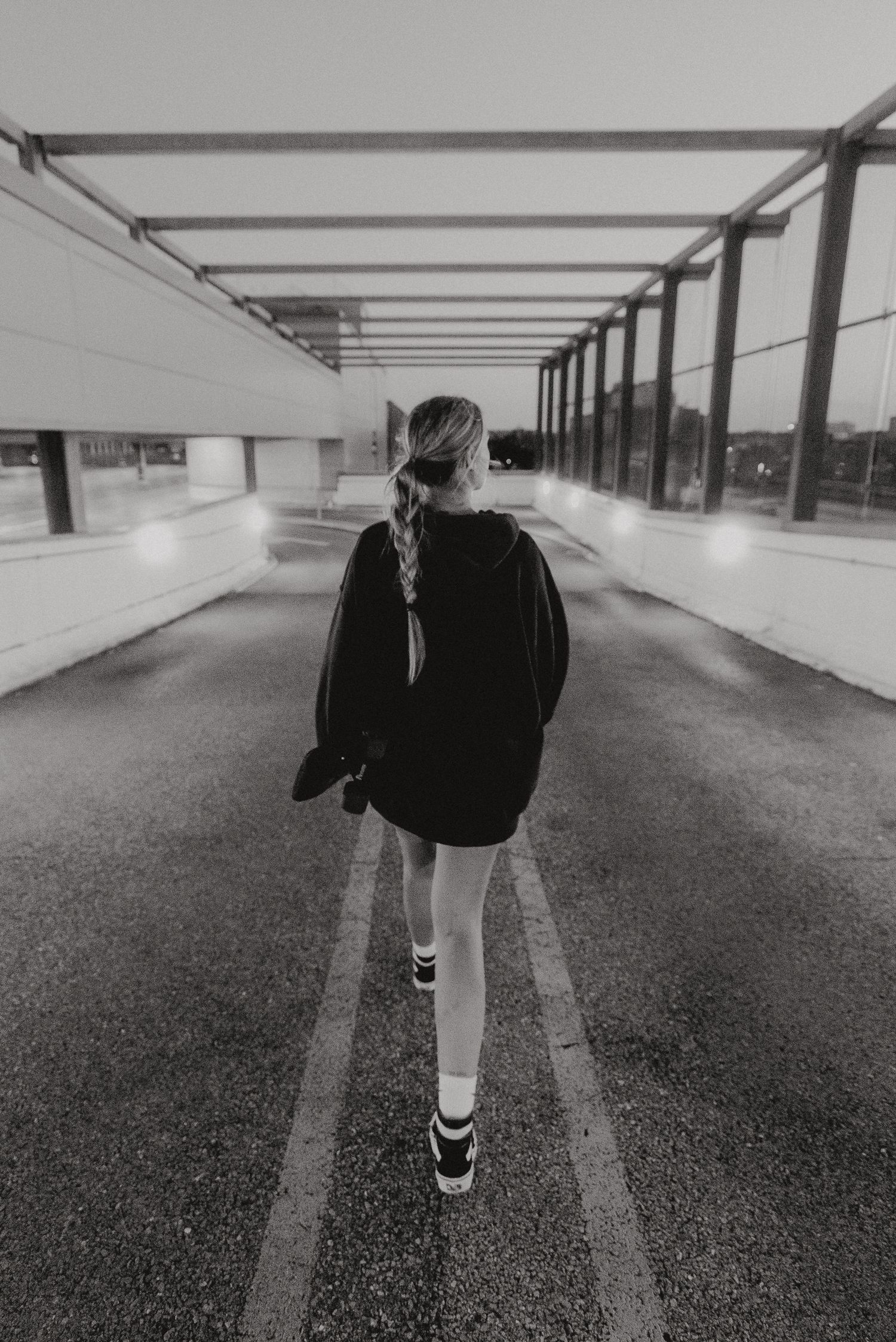 Black and white photo of someone walking through a covered walkway with geometric lines.
