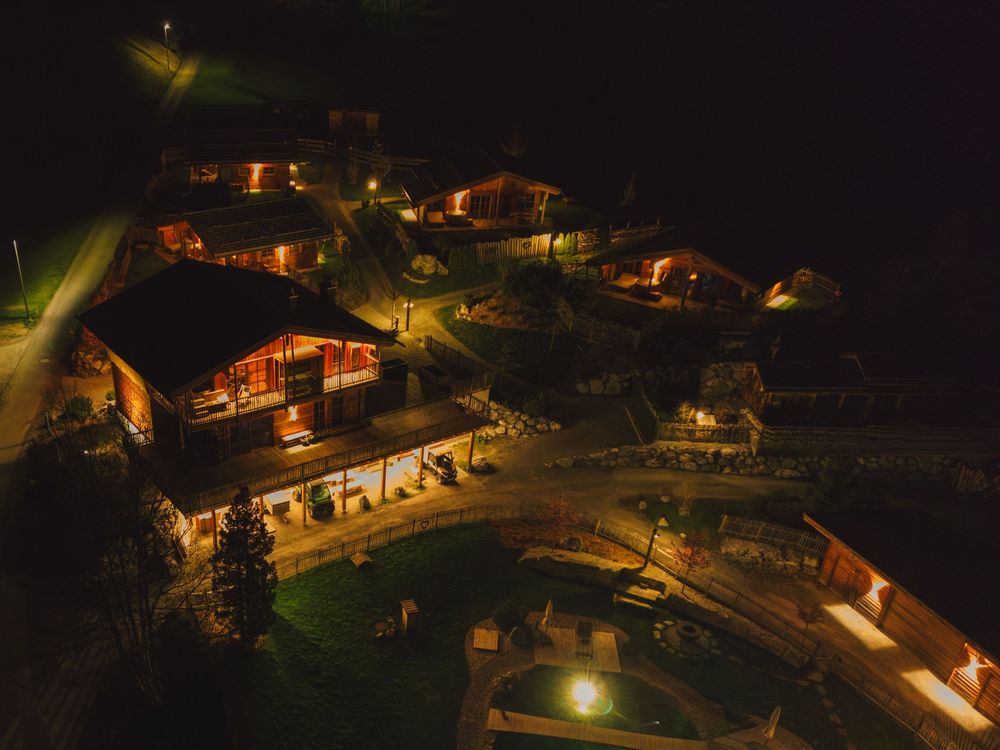 Aerial view of illuminated resort cabins and pathways at night.