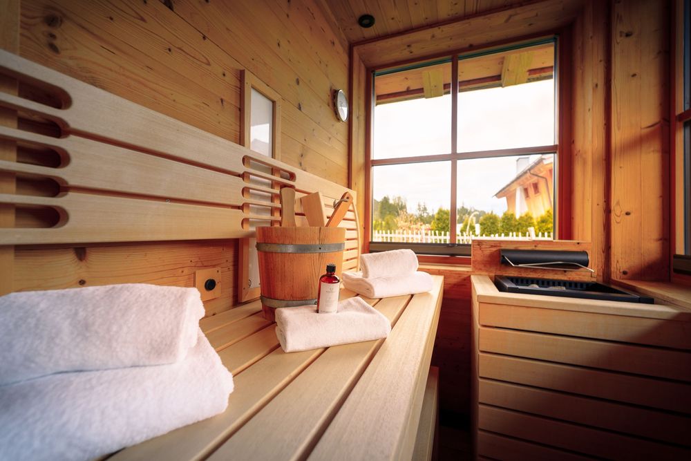 Sunlit interior of a wooden cabin with panoramic windows and natural light.