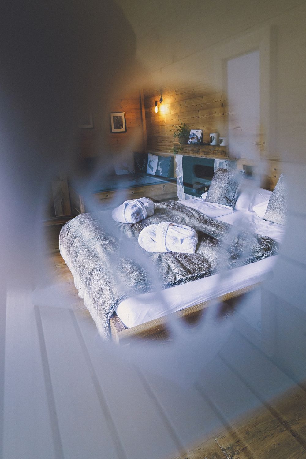 Cozy bed with white linens and pillows in a dimly lit bedroom interior.