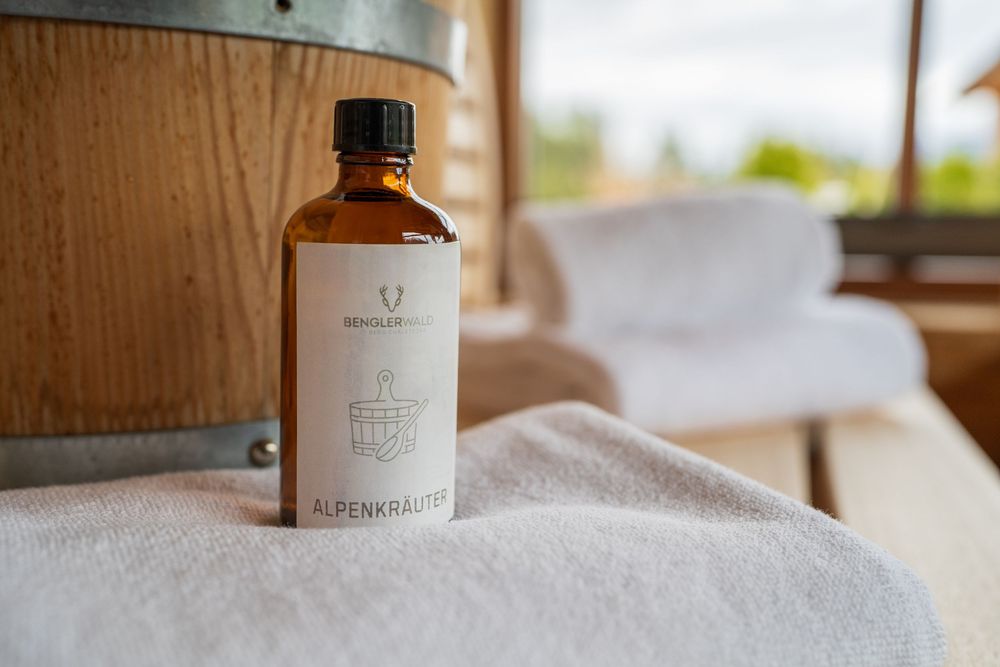 Brown glass bottle on white towel in spa setting with natural lighting.