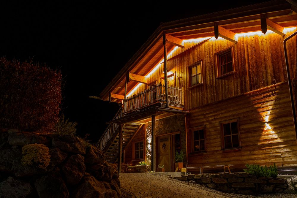Rustic wooden mountain cabin illuminated at night with warm glowing windows.