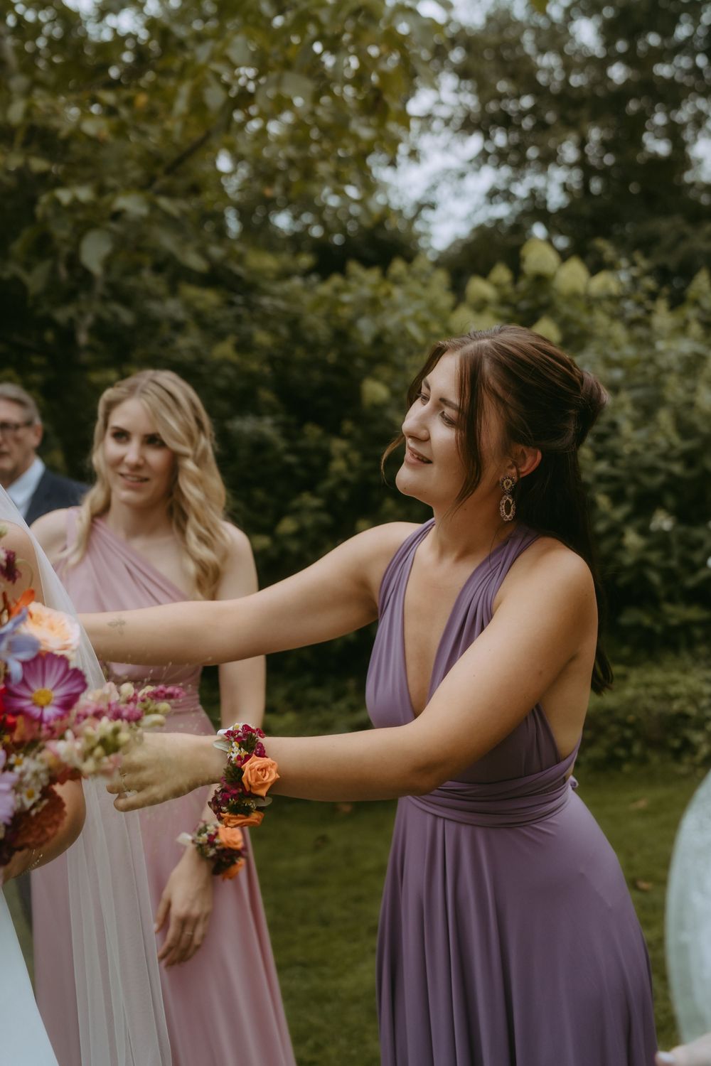 Bridesmaids in purple dresses sharing joyful moments outdoors during wedding celebrations.