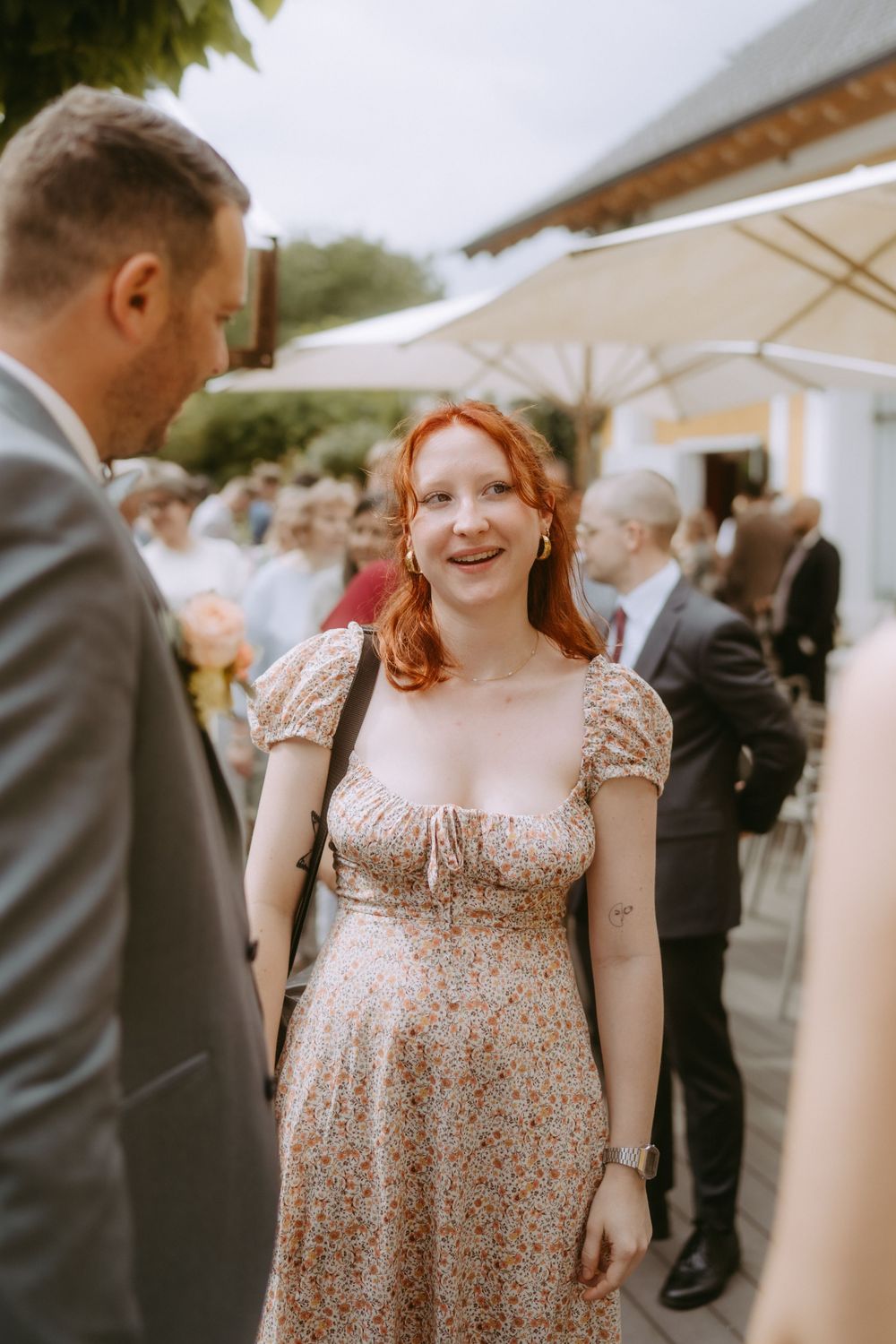 Guest in a floral dress mingling at an elegant outdoor wedding reception.