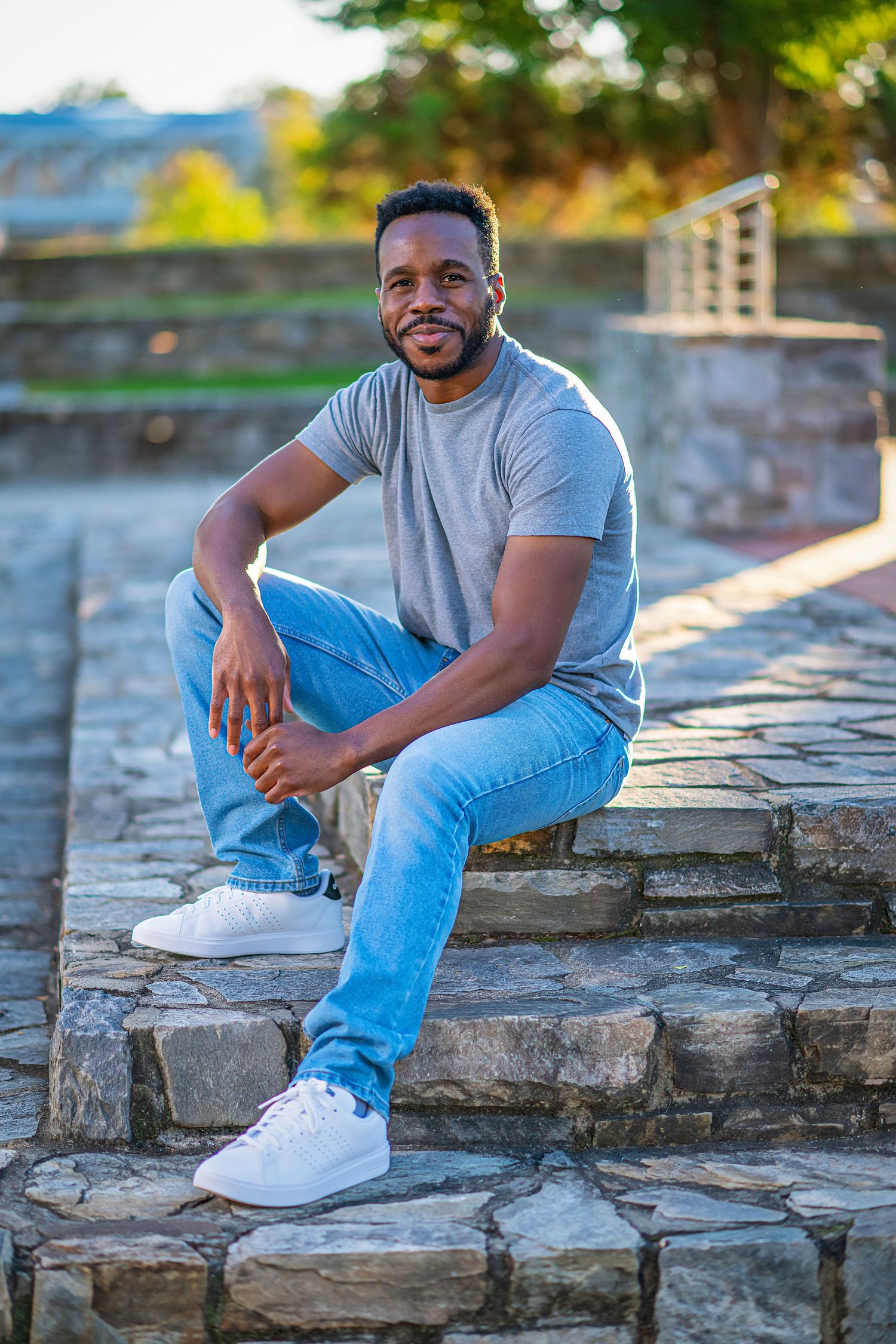 Four connected photos show someone in light blue jeans and gray t-shirt posing casually against a beige brick wall.