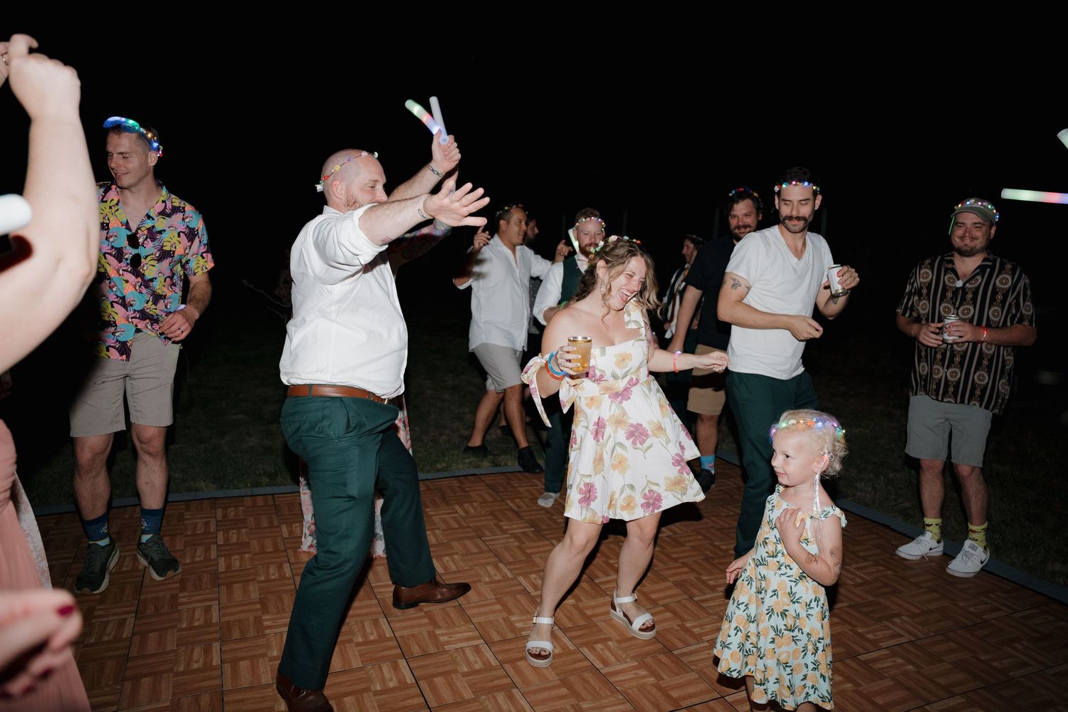 People dancing together on a wooden dance floor at a lively social gathering.
