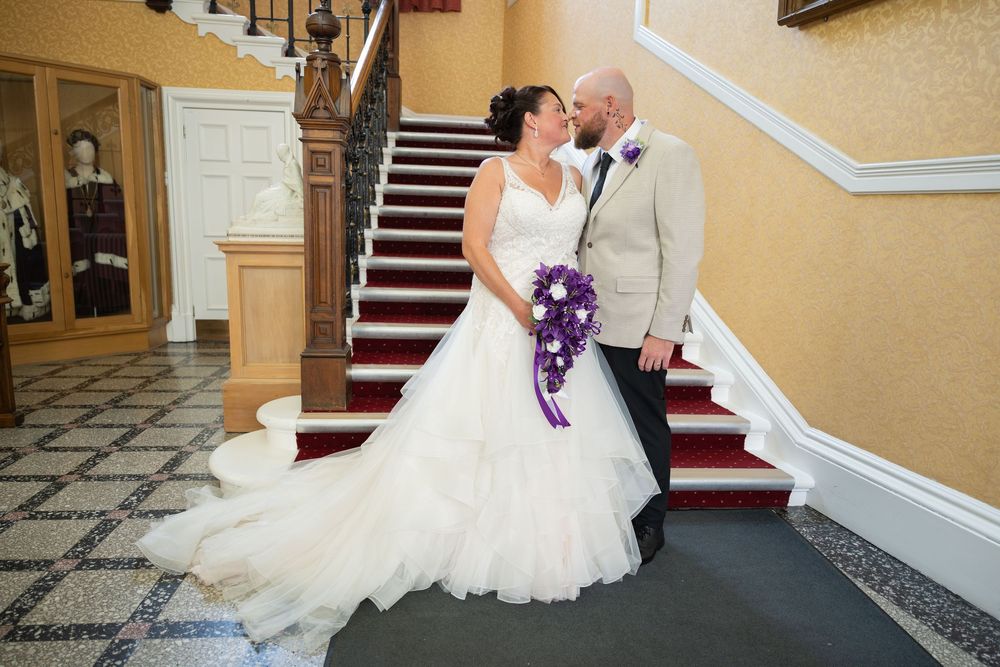 Wedding couple posing in front of classic architectural details and yellow walls.