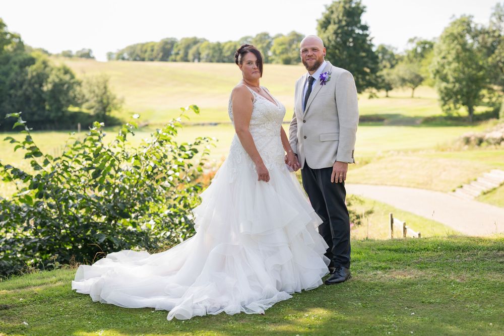 Wedding portraits taken in a sunny outdoor setting with natural landscape.