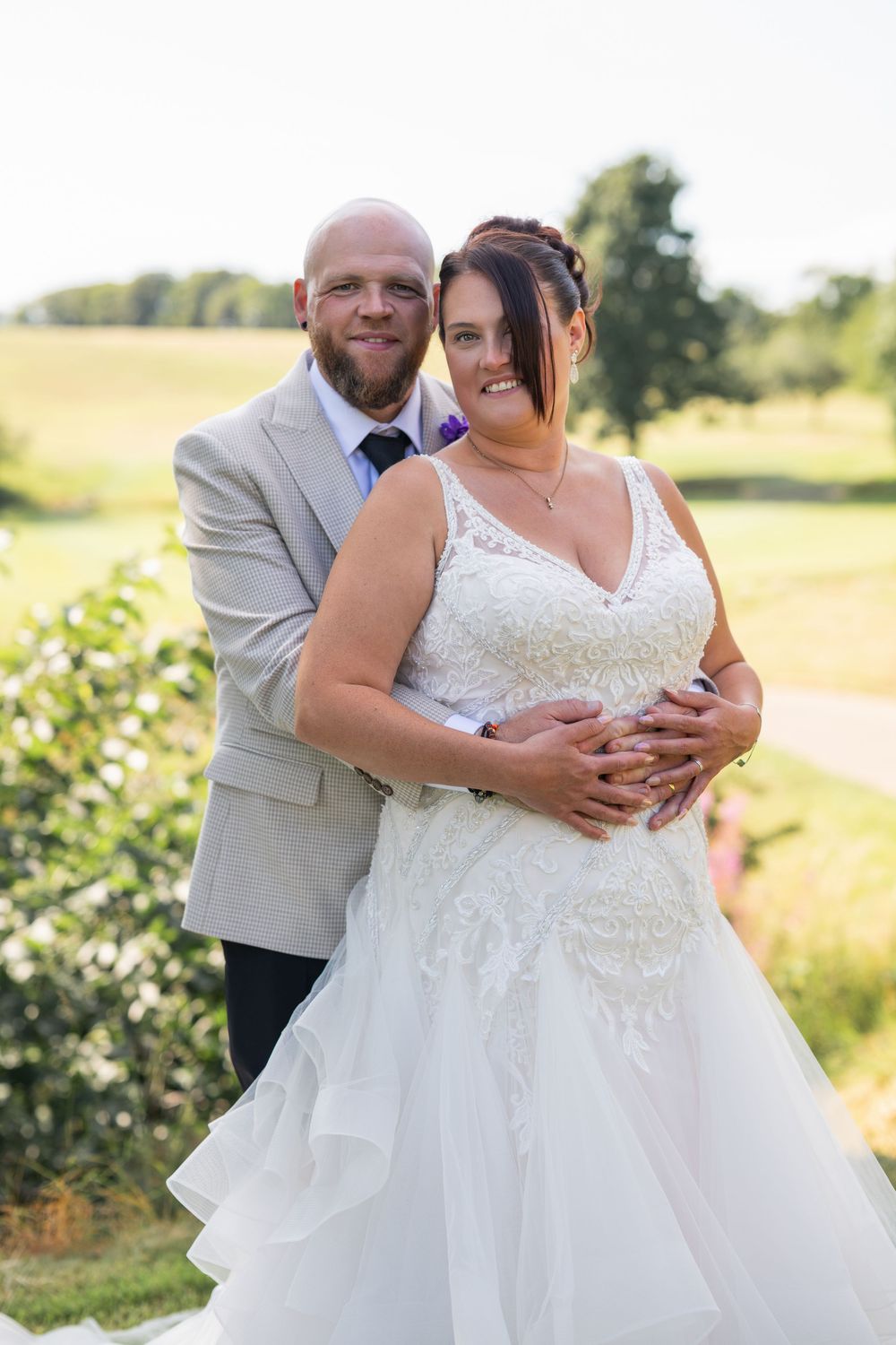 Romantic outdoor wedding photos captured in a sunny field setting.