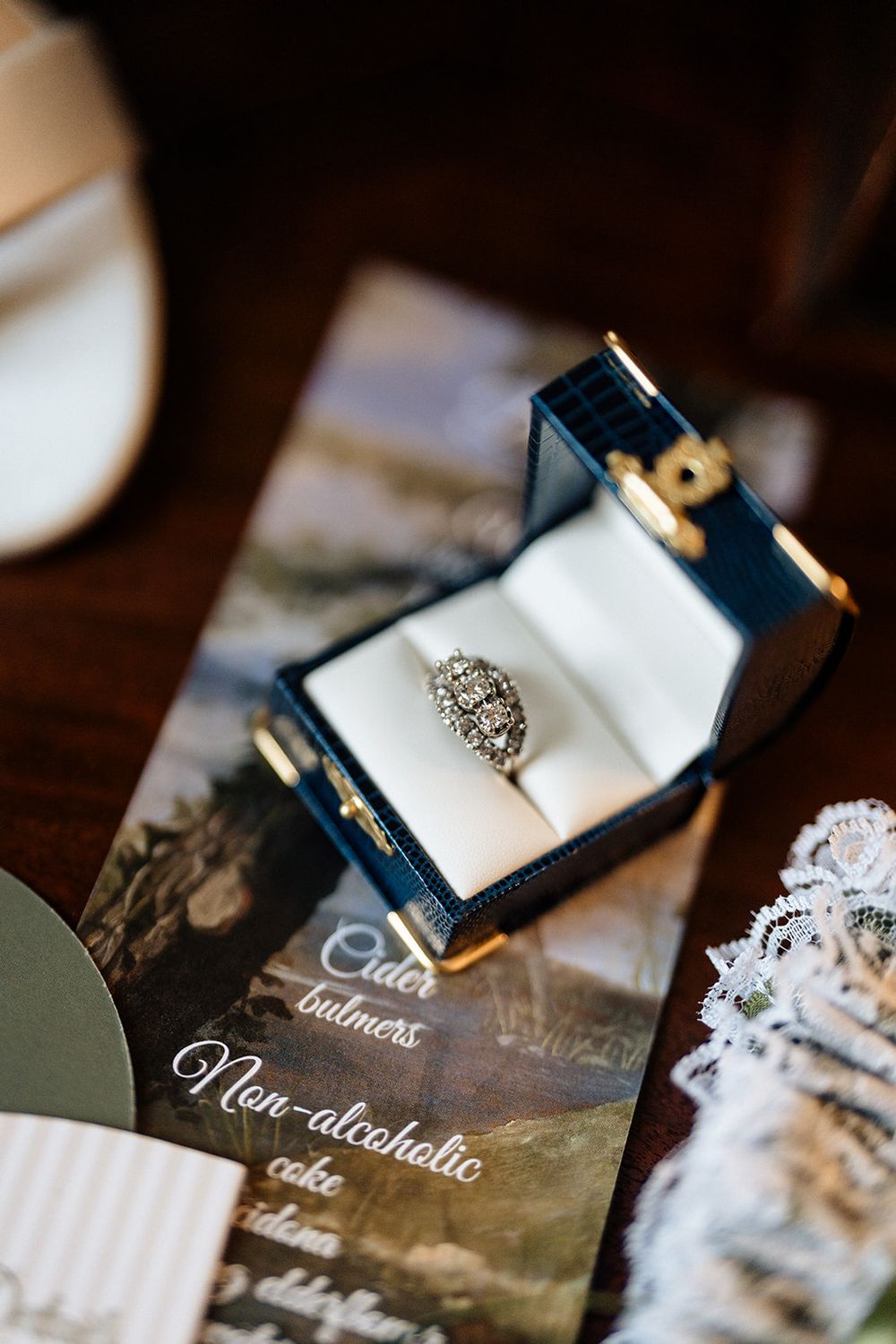 Wedding place cards with elegant calligraphy on dark navy paper sit in luxurious white velvet ring boxes.