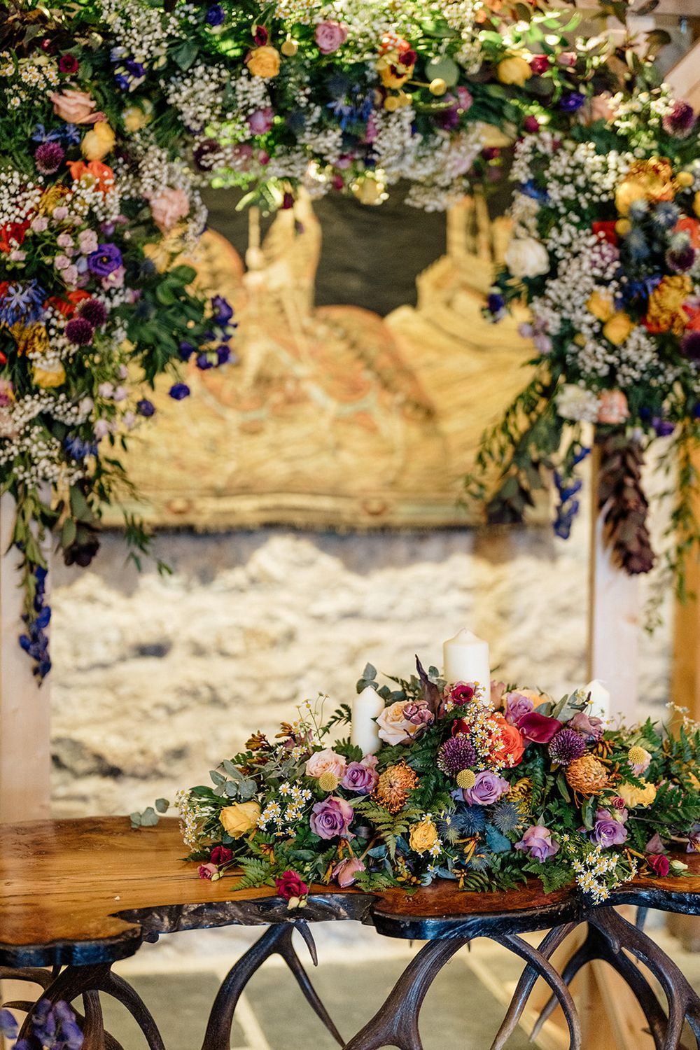 Vintage bicycles decorated with colorful floral arrangements and navy blue ribbons displayed against a rustic stone wall.