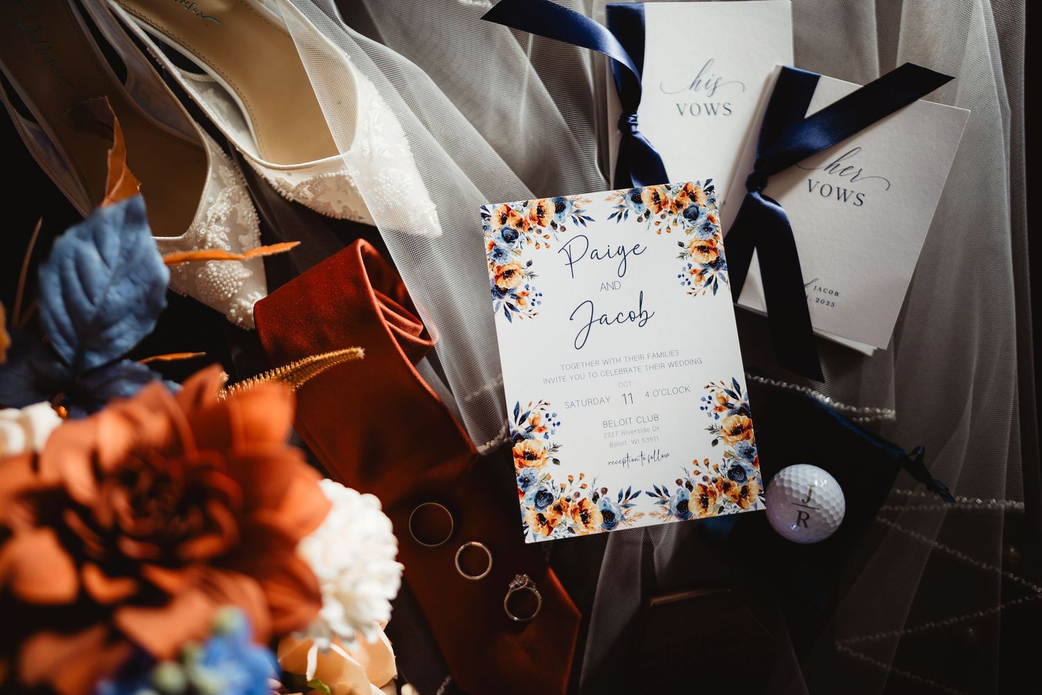 Wedding invitation card with floral design elements surrounded by flowers and wedding decor details in natural lighting.