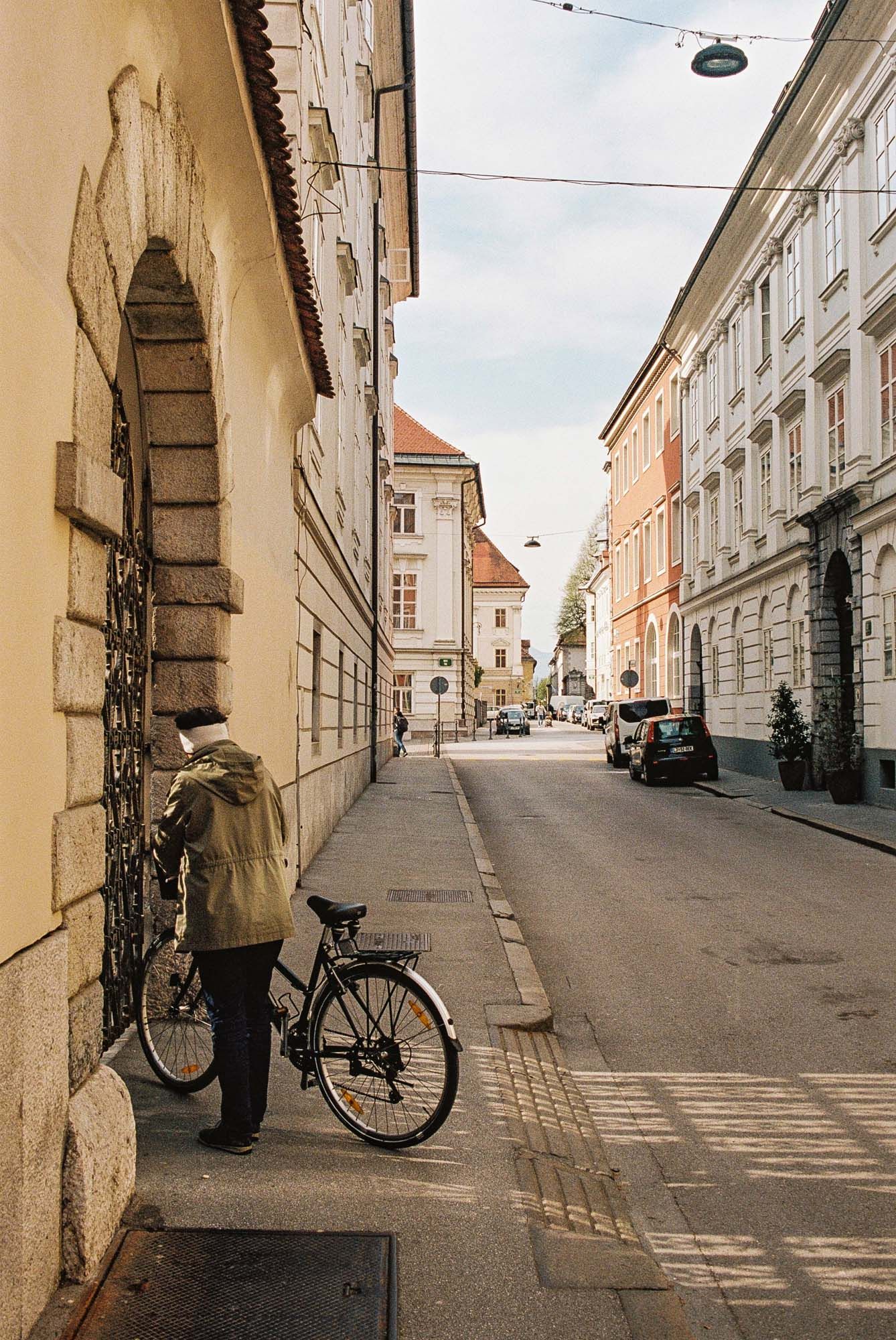 Panoramic view of a quiet European street with historic buildings, arched walkways, and a parked bicycle.
