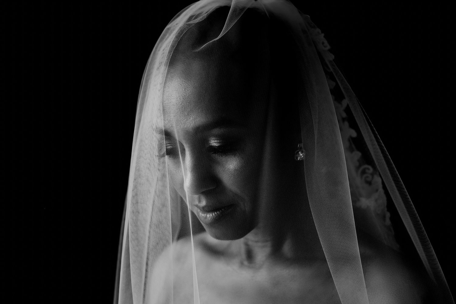 Dramatic side profile of a bride wearing a delicate veil in black and white.