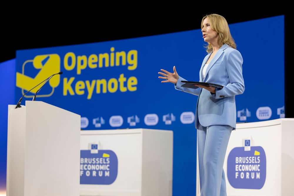 Professional conference stage setup with blue backdrop and company branding.