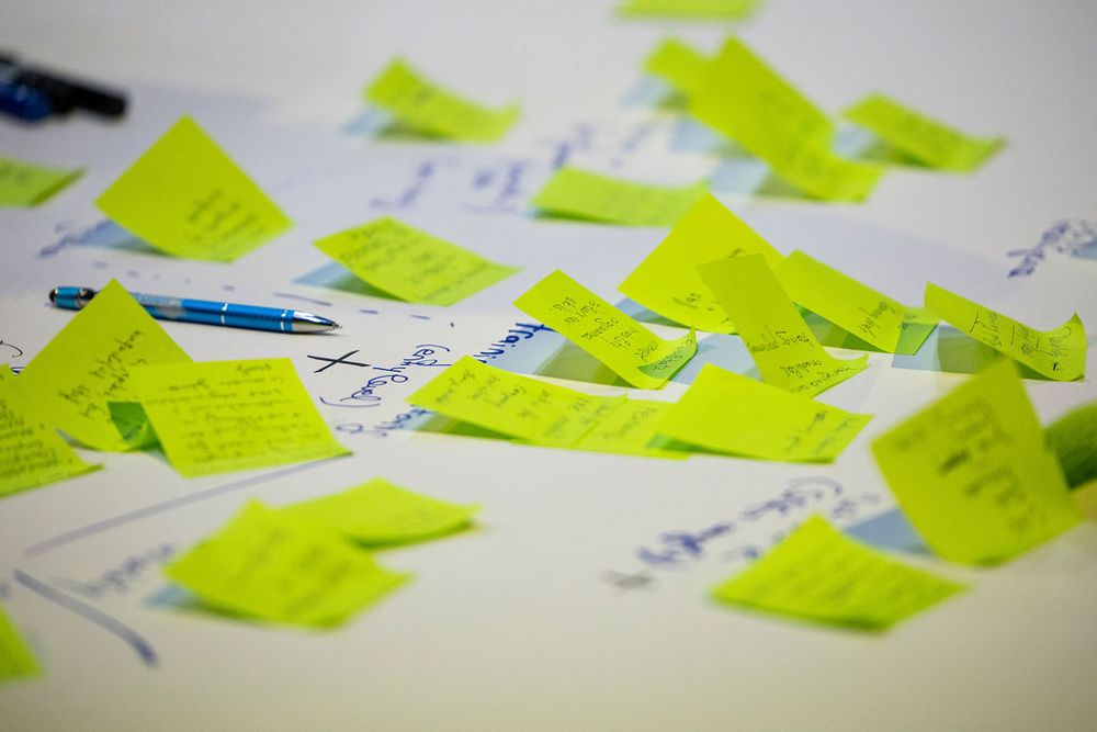 Collection of bright yellow sticky notes spread across a white surface with handwritten notes.