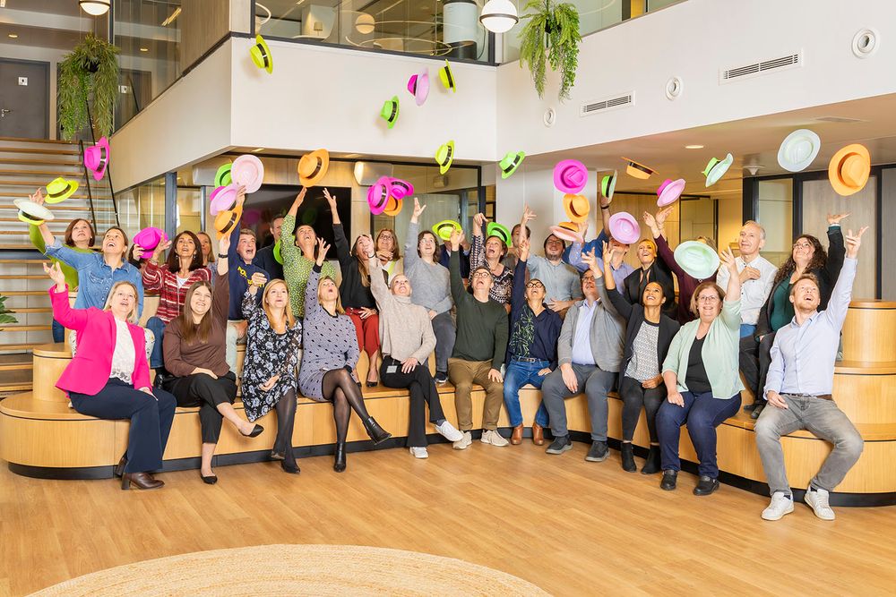 Group photo of employees lined up against a wall in a modern office space.
