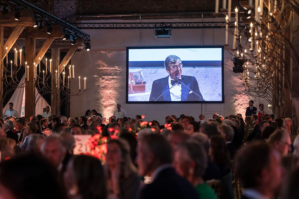 Large audience gathered in a dimly lit venue for a corporate event or conference presentation.