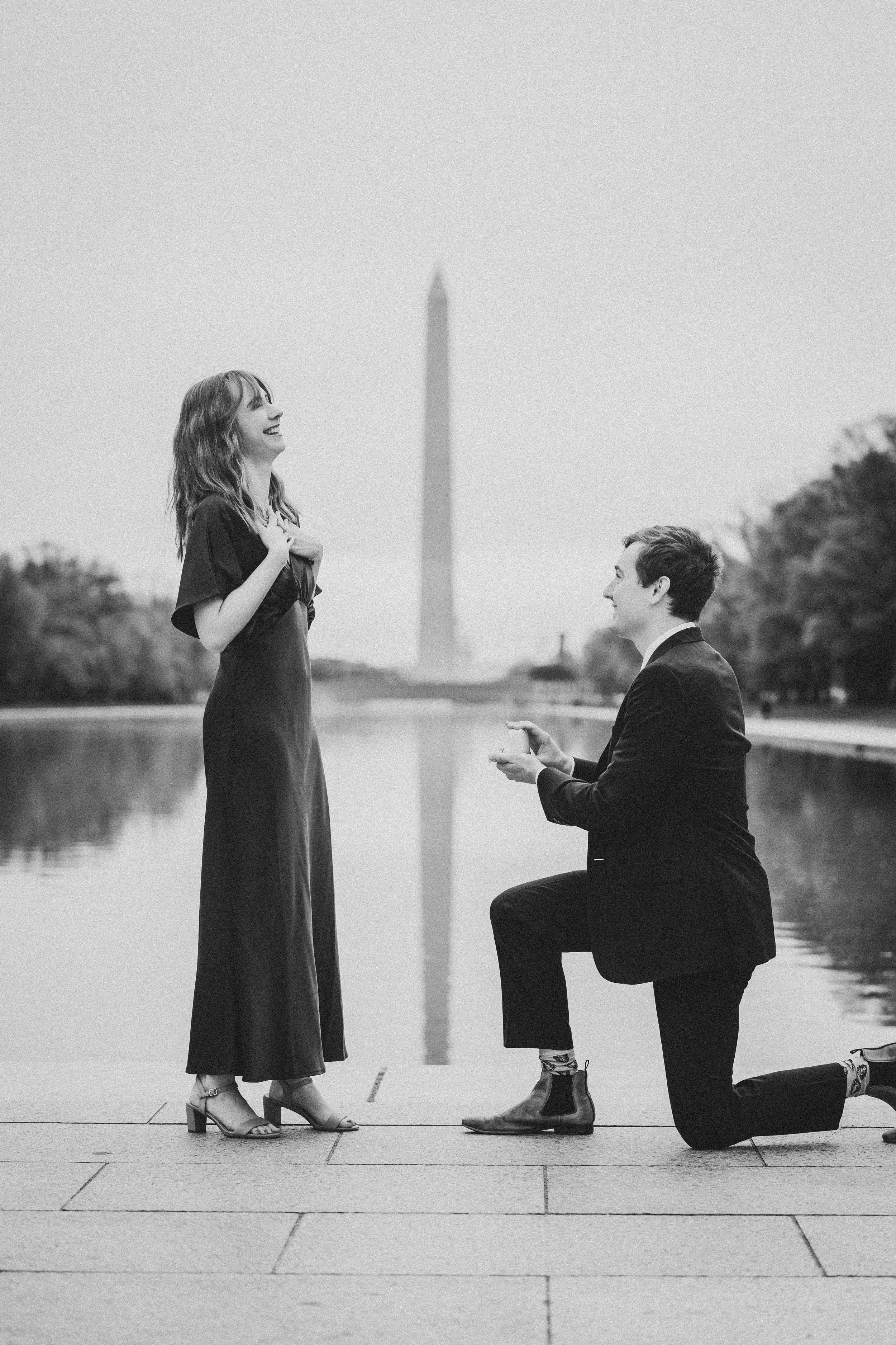 A romantic proposal sequence showing a couple by the Washington Monument reflecting pool in black and white photography.