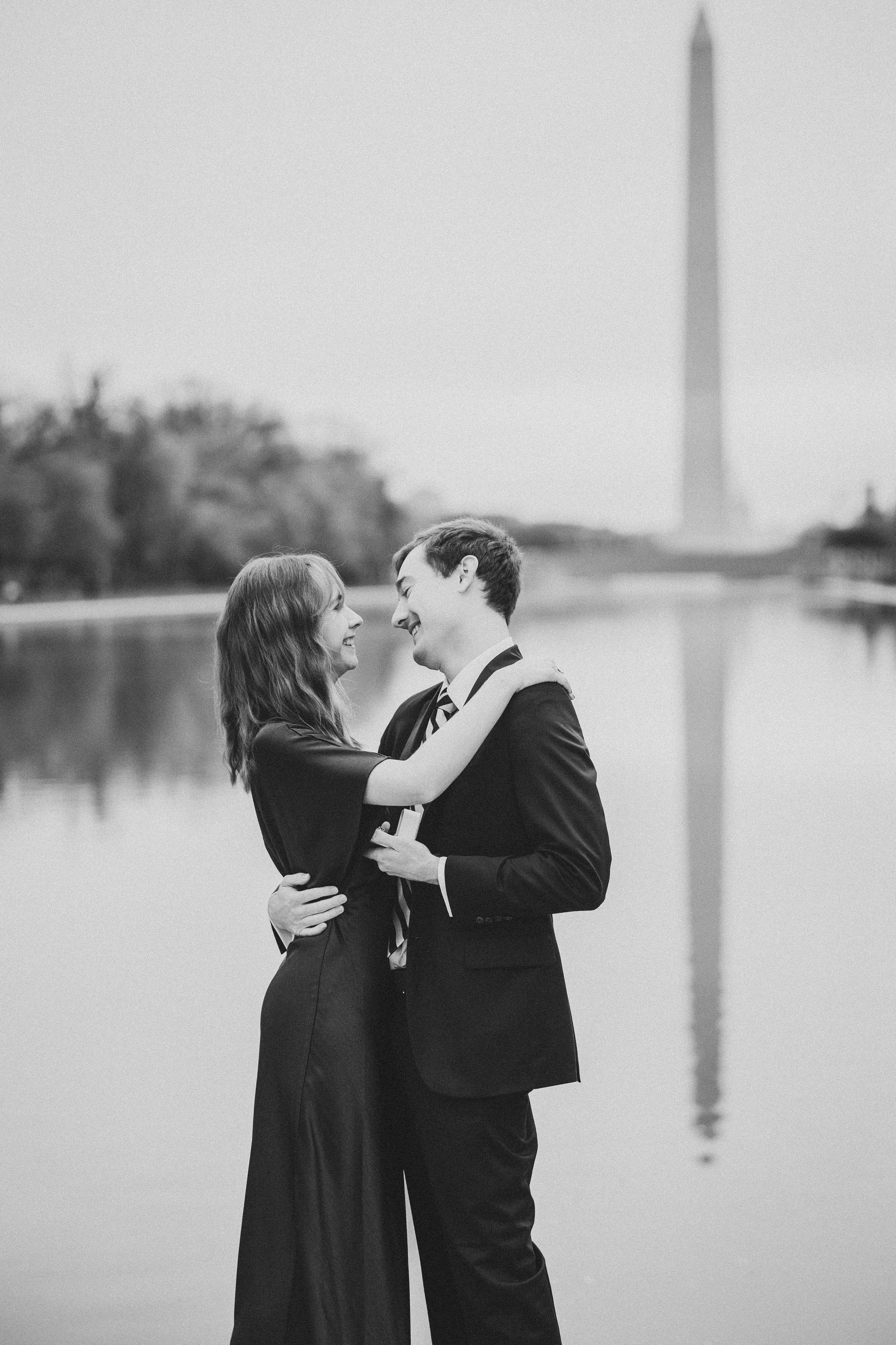 A romantic couple shares intimate moments in black and white with the Washington Monument in the background.