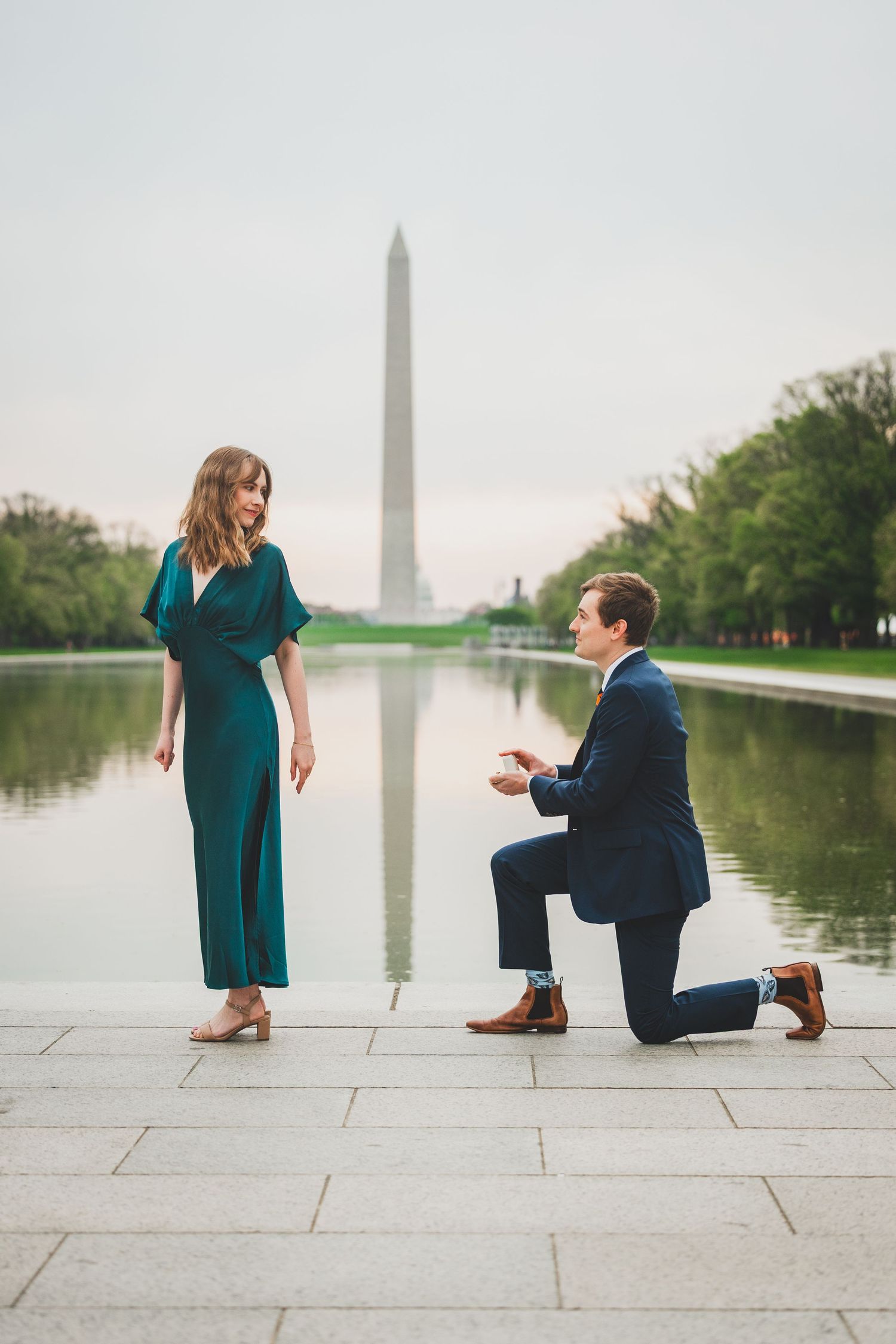 A romantic proposal scene unfolds at the National Mall with the Washington Monument reflecting in the pool.