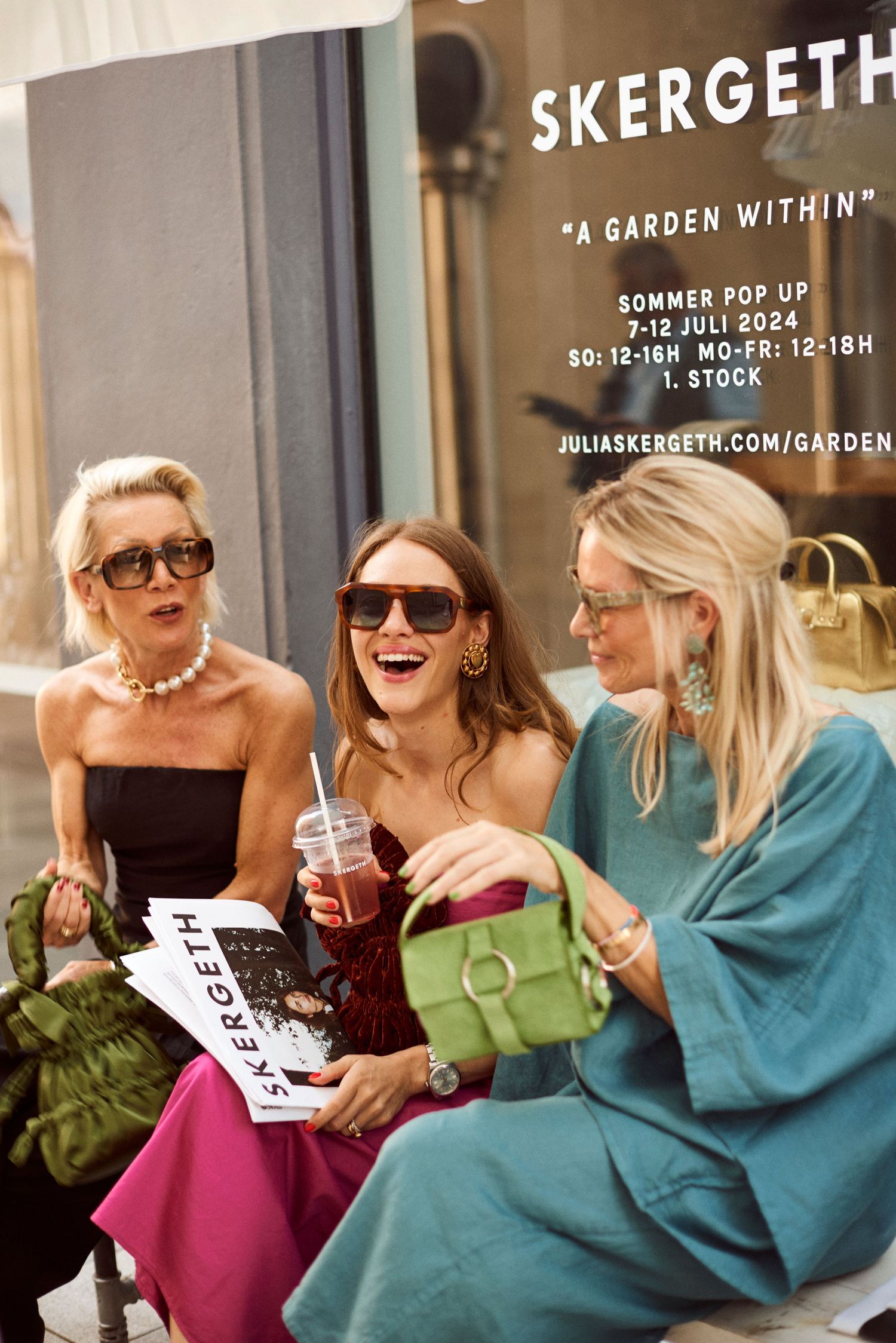 Three stylish women laughing together outside Skergeth Garden Within summer pop-up shop in 2024.
