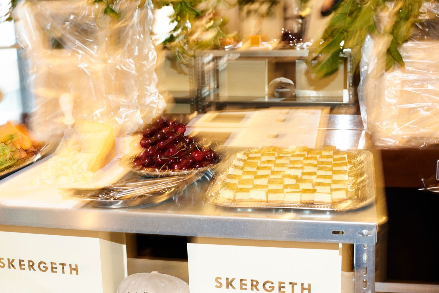 Skergeth branded food display with checkerboard pastries and fresh cherries on silver tray.