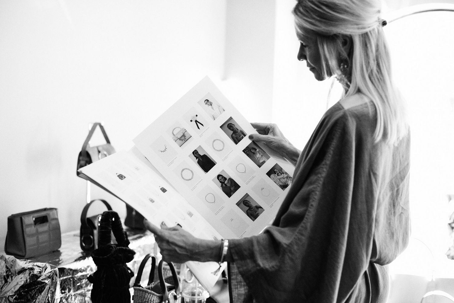 Blonde woman in black robe browsing Skergeth lookbook catalog in black and white photo.