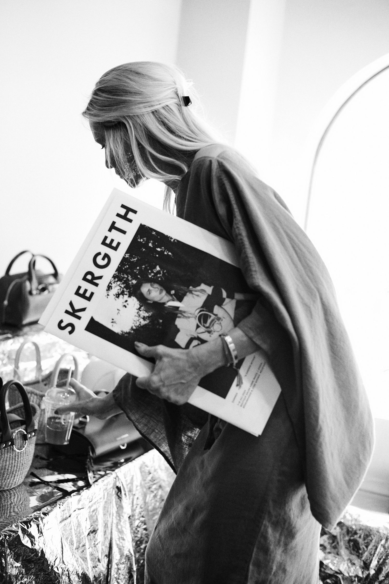 Black and white image of woman reading Skergeth magazine at a fashion pop-up event.