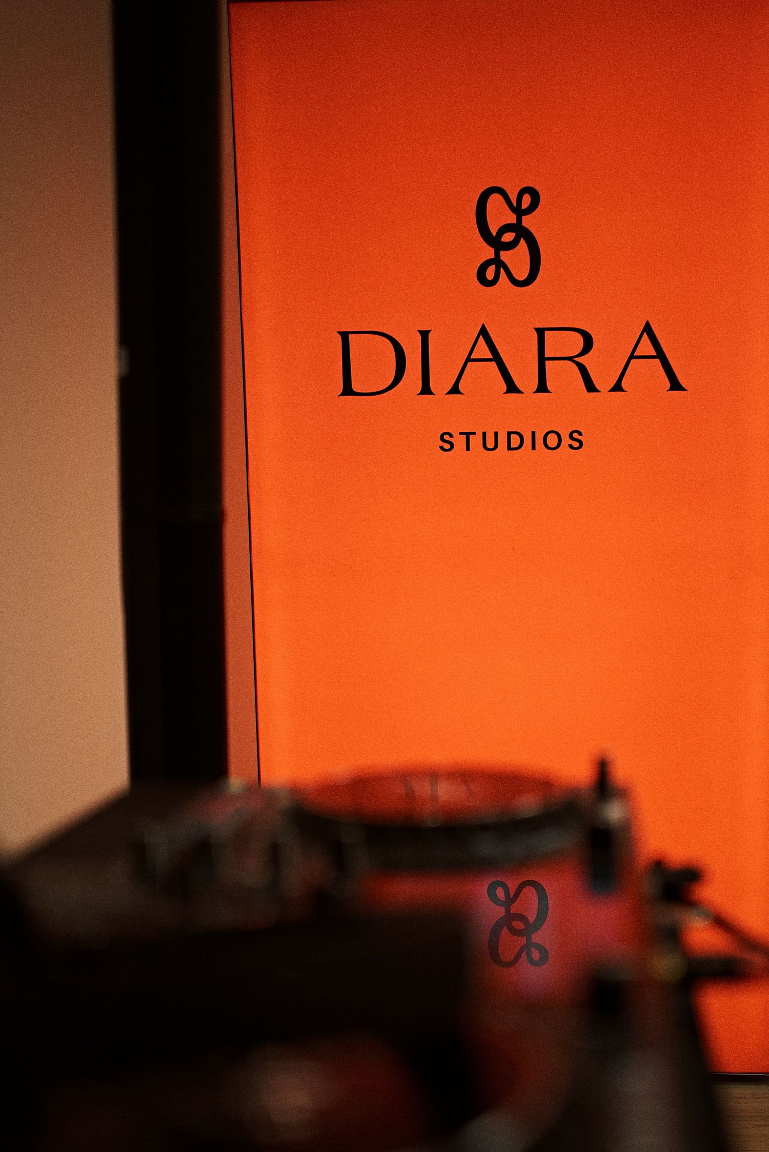 Diara Studios orange branded logo sign with turntable in foreground at studio event.