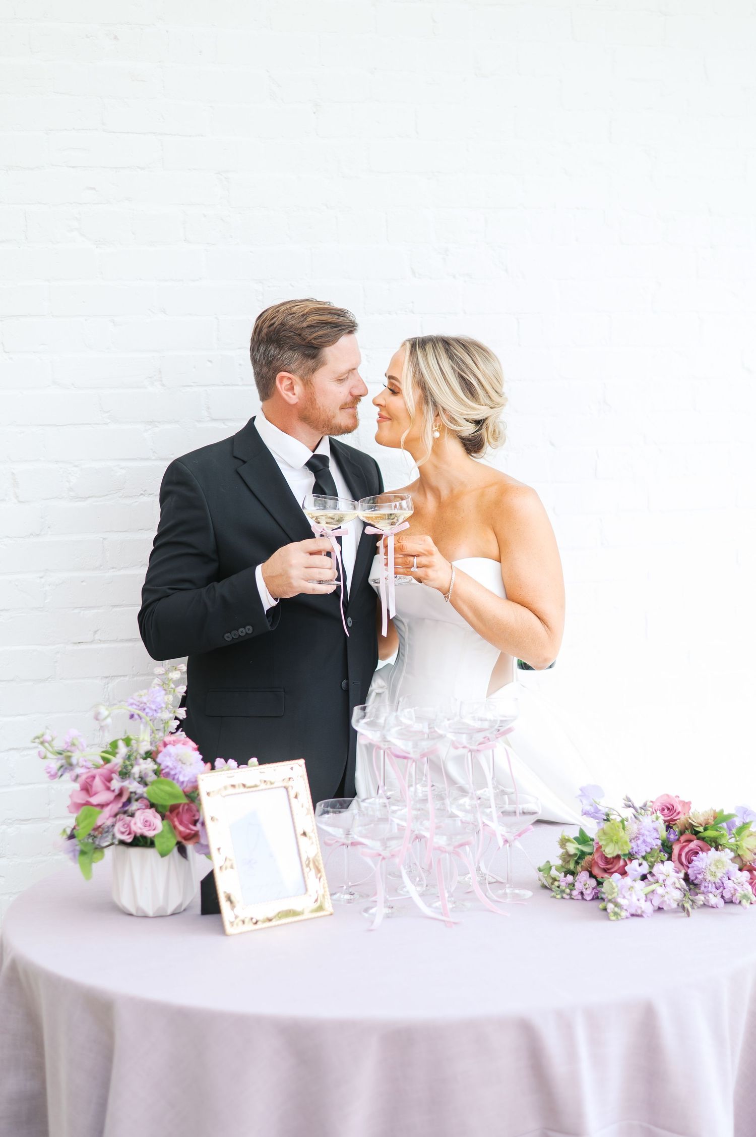 Couple in formal attire toasting with champagne at an elegant purple-themed reception table by fayetteville NC wedding photographer