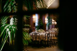 A dimly lit outdoor restaurant patio with empty tables and chairs illuminated by string lights and lanterns at night.