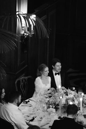 Elegant wedding reception dinner table with candlelight and floral centerpieces as guests dine in formal attire.