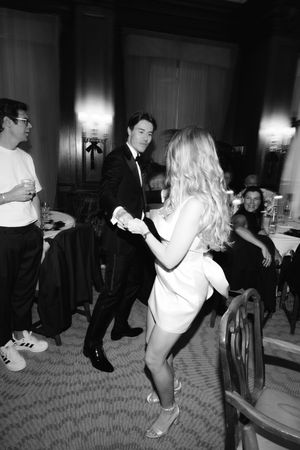 Energetic dance party scene in black and white showing people dancing at a formal event.