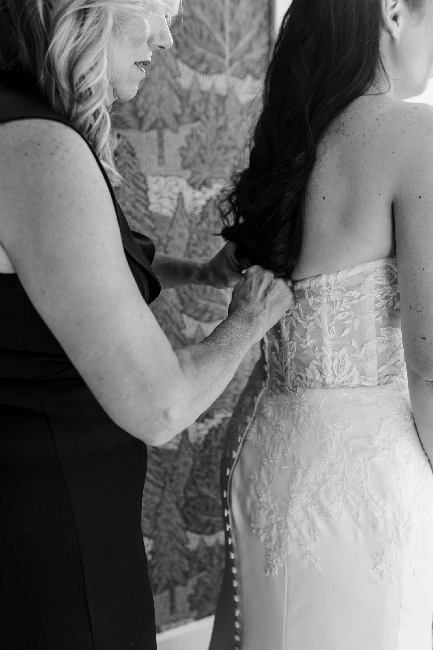 Close-up details of a white wedding dress with delicate lace embellishments and button closures along the back.