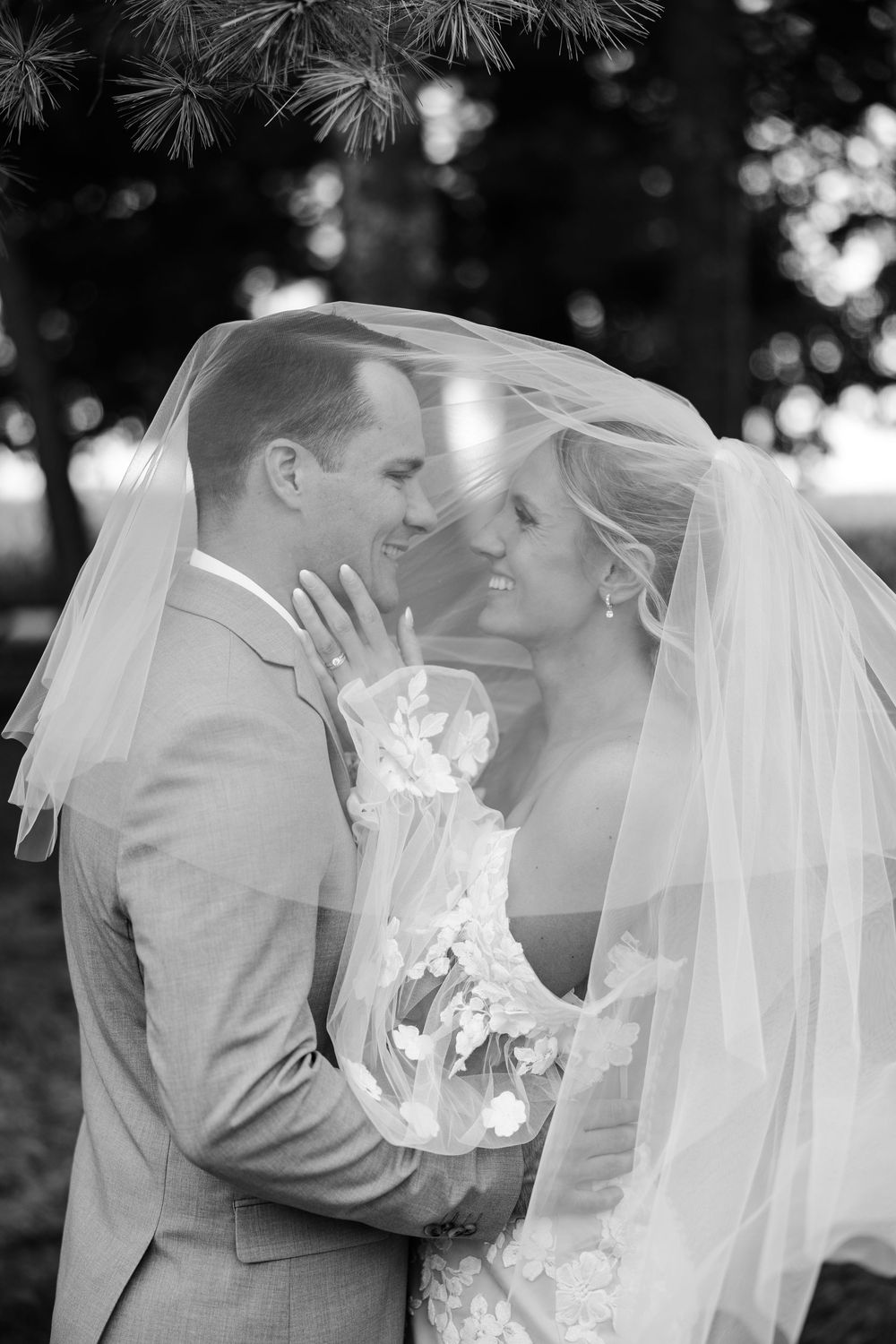 A romantic black and white wedding photo sequence showing a couple sharing tender kisses under a flowing white veil.