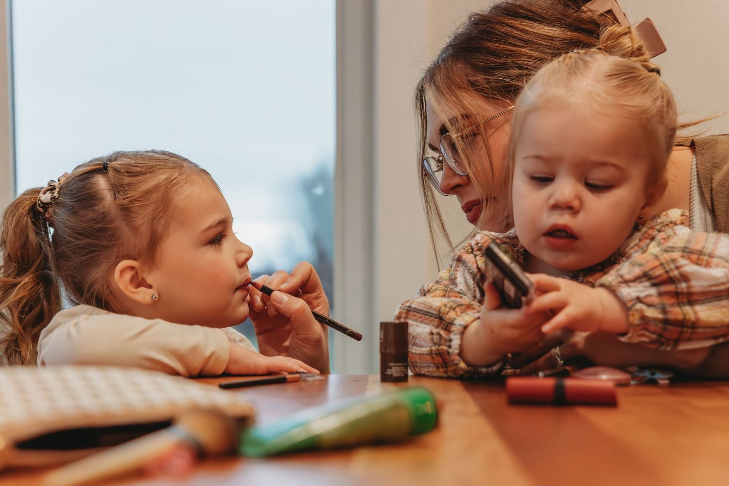 Two children sitting at table engaging with craft materials together.